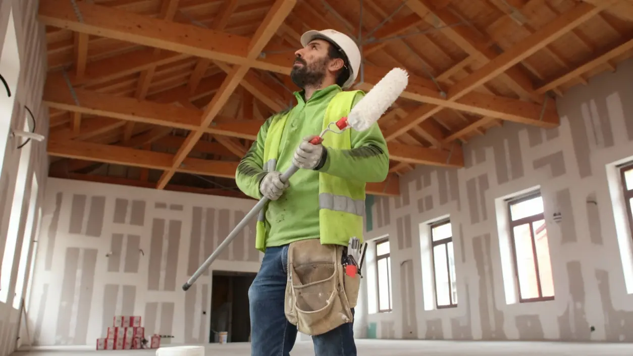 Una persona con attrezzatura da pittura osserva il soffitto in un edificio in ristrutturazione