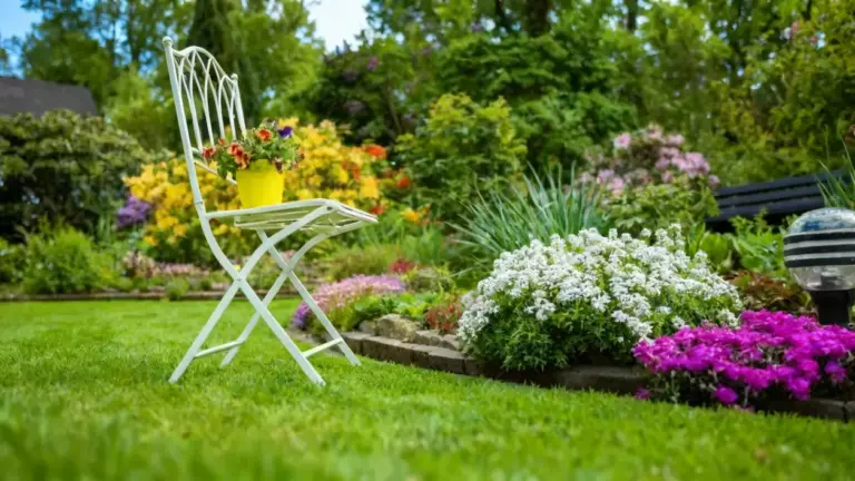 Sedia da giardino bianca con un vaso di fiori in un giardino ben curato