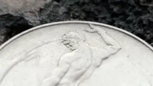 Dettaglio ravvicinato di una moneta da 50 lire del 1958 con figura maschile in rilievo