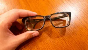 Occhiali con lenti opache tenuti in mano su superficie di legno