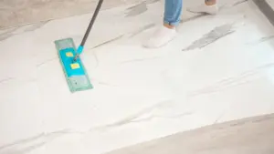 Una persona pulisce un pavimento chiaro con un mocio piatto