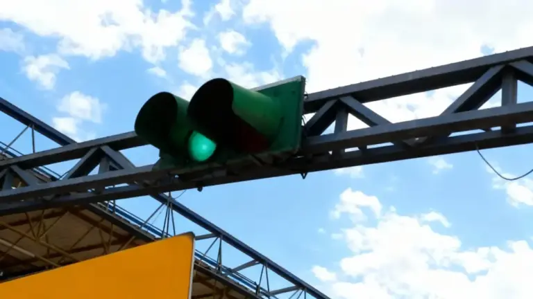 Semaforo verde sopra un casello autostradale sotto il cielo azzurro