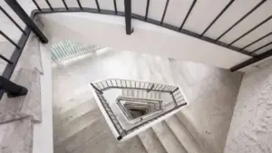 Scala condominiale vista dall'alto con gradini in marmo chiaro e ringhiere metalliche