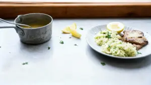 Piatto di scaloppine al limone con contorno di riso e fetta di limone su un tavolo chiaro