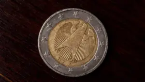 Moneta da due euro con simbolo di un'aquila su sfondo in legno scuro