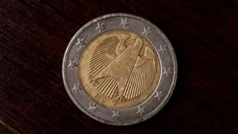 Moneta da due euro con simbolo di un'aquila su sfondo in legno scuro