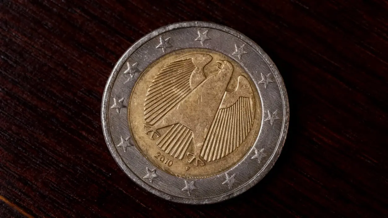 Moneta da due euro con simbolo di un'aquila su sfondo in legno scuro