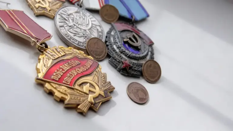 Vecchie medaglie e monete sovietiche disposte su una superficie chiara